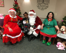 Santa Claus and company pose for a photo with one of the children at the party.